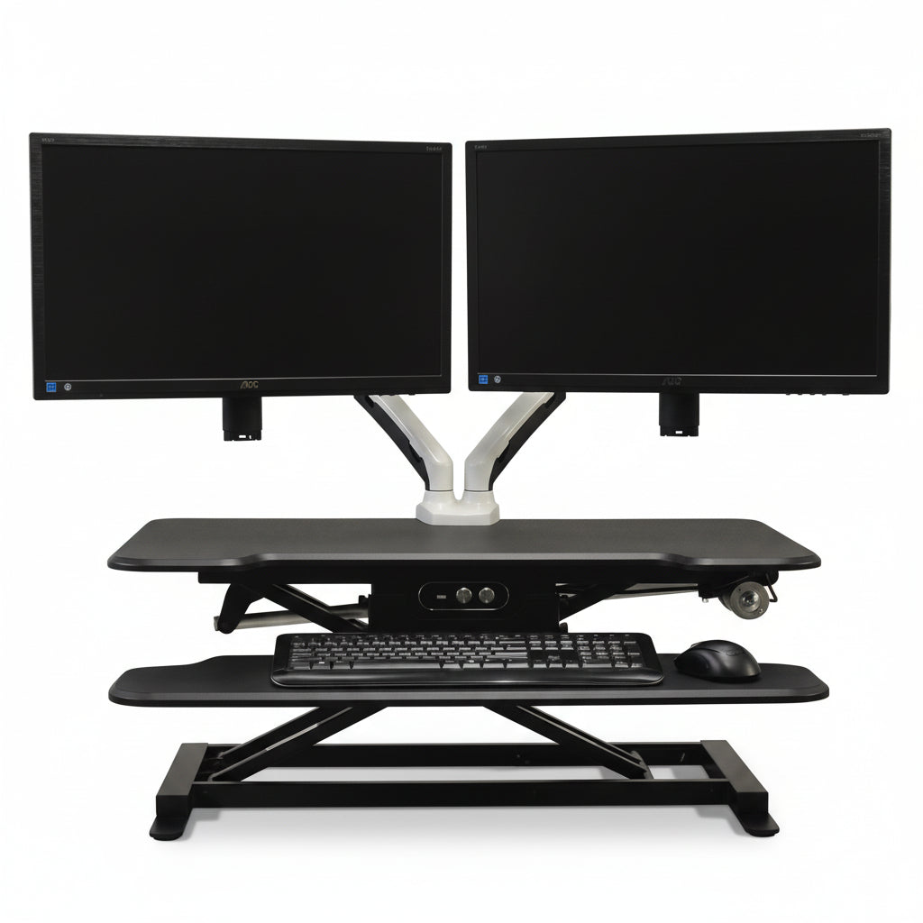 An electric standing desk converter with a black tabletop, supporting two monitors, a keyboard, and a mouse. It has an integrated USB charging port and is designed for minimal assembly.